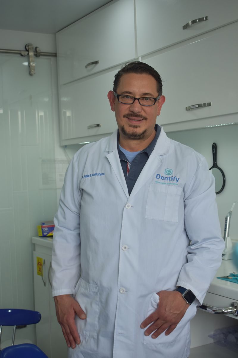 Portrait of a male dentist in a modern dental clinic, standing confidently in his white coat.